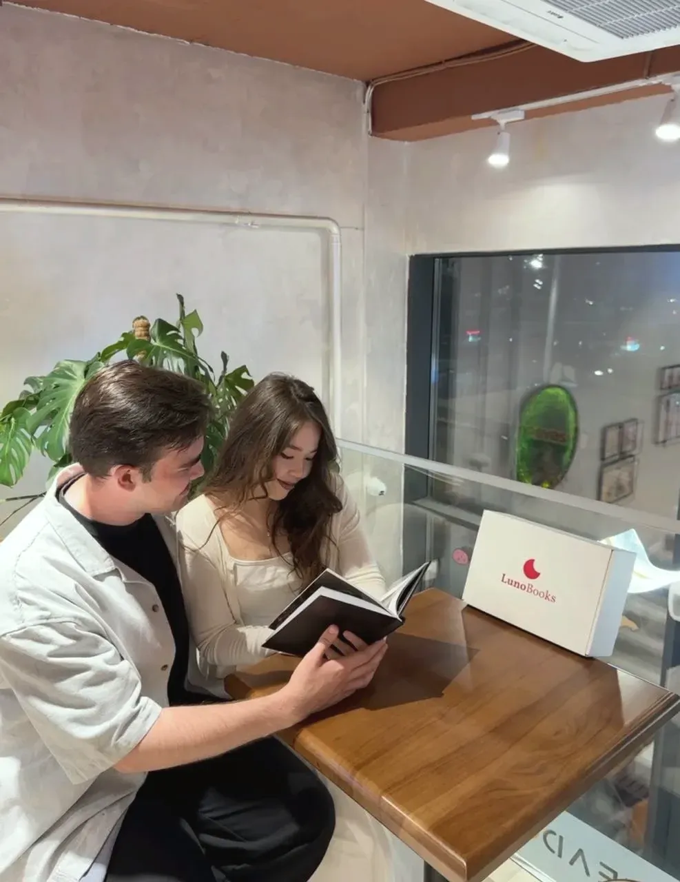 Пара читает книгу LunoBooks в кафе, рядом коробка